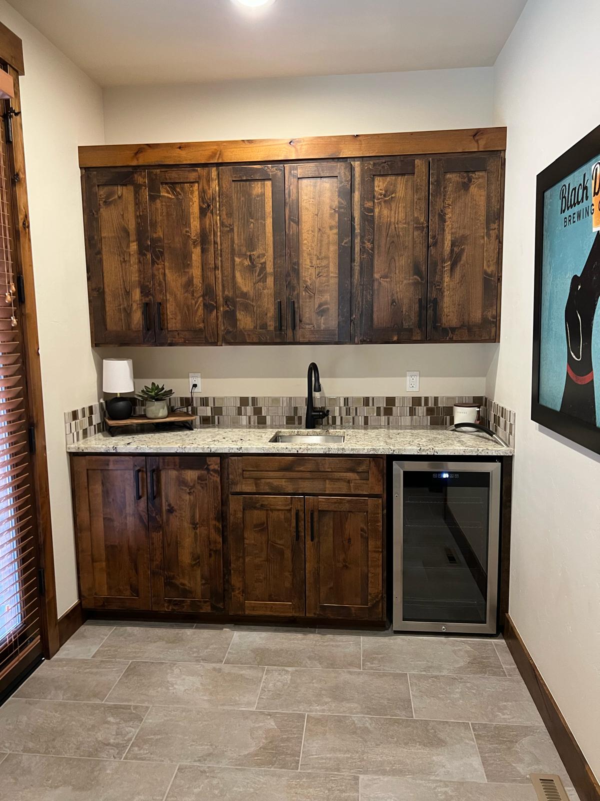 Custom wet bar with wine cooler, granite top and dark stained cabinetry