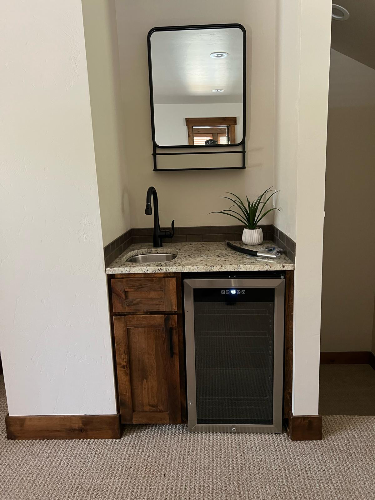 Built-in beverage station with mini fridge and granite countertop