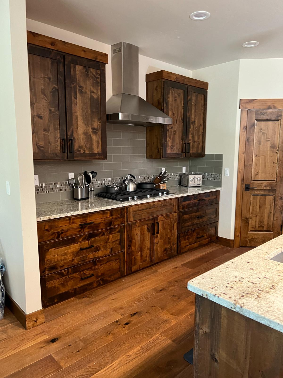 Dark alder cabinetry with mosaic tile backsplash and gas range